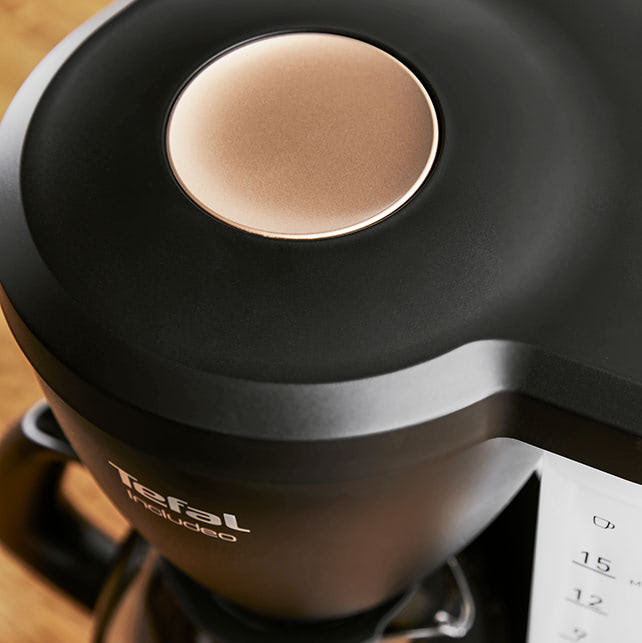 Cafetière filtre Includeo vue de haut avec un zoom sur le large bouton poussoir permettant une ouverture facile du couvercle