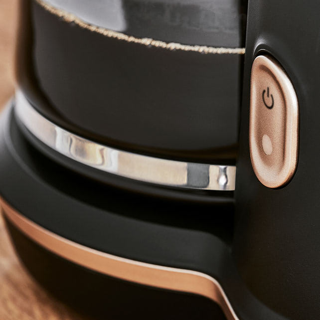 Cafetière filtre Includeo avec un zoom sur le gros bouton d'allumage très visible et sa base élargie pour une meilleure stabilité